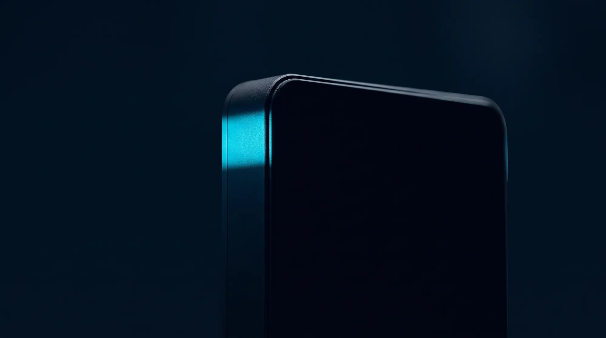 A single band of electric cyan light falling across the edge of a dark object, everything else in shadow.