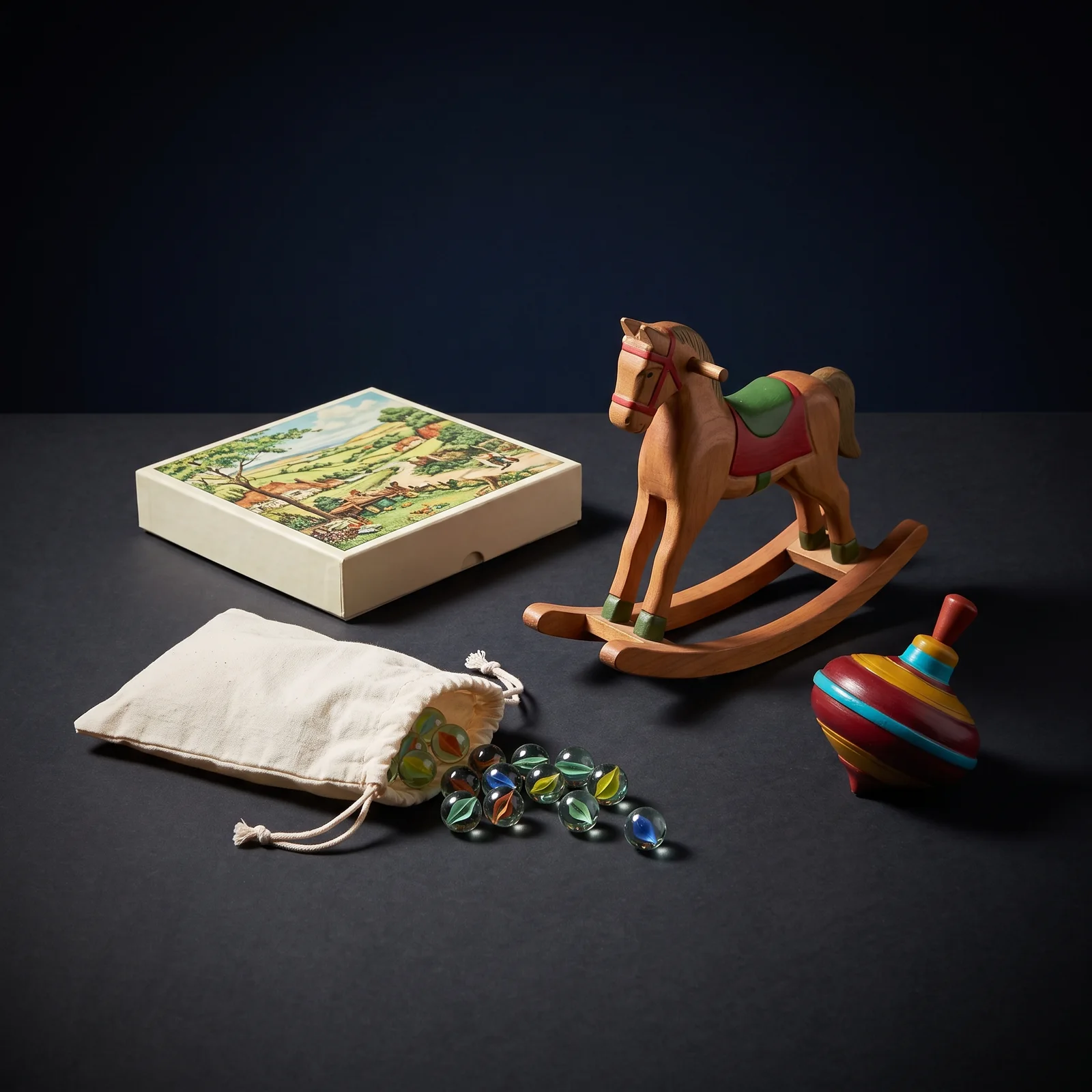 A boxed jigsaw with a bright intact lid, a cotton drawstring bag spilling about a dozen clear glass marbles, a carved wooden rocking horse with even paintwork and a brightly painted spinning top.